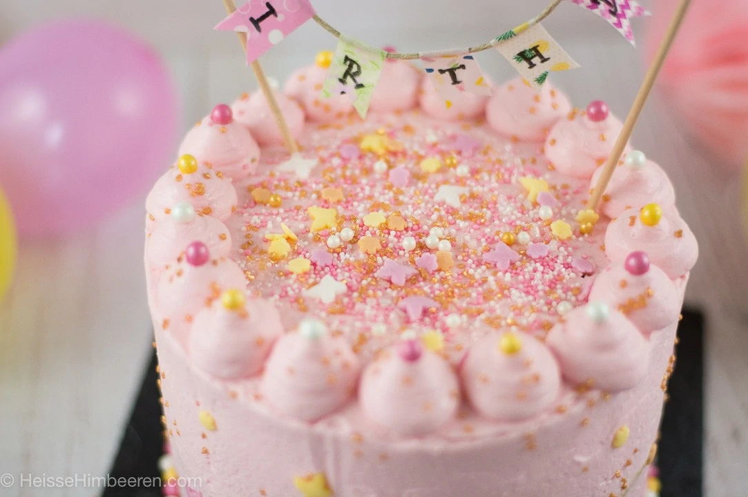 Geburtstagstorte 1 Jahr in der Nahaufnahme. Man sieht viele bunte Streusel auf einer rosa Torte.
