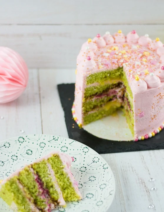 Die Geburtstagstorte ist angeschnitten. Die Torte ist rosa und innen ist der Teig grünlich.