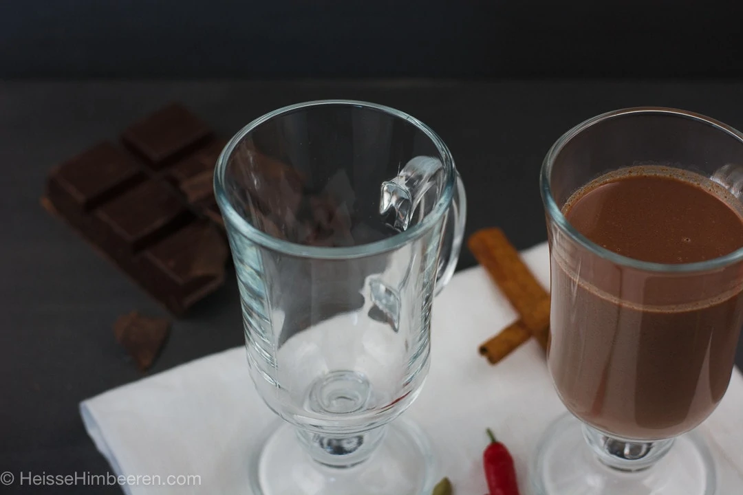 Ein leeres Glas und ein Glas mit heißer Schokolade selber gemacht.