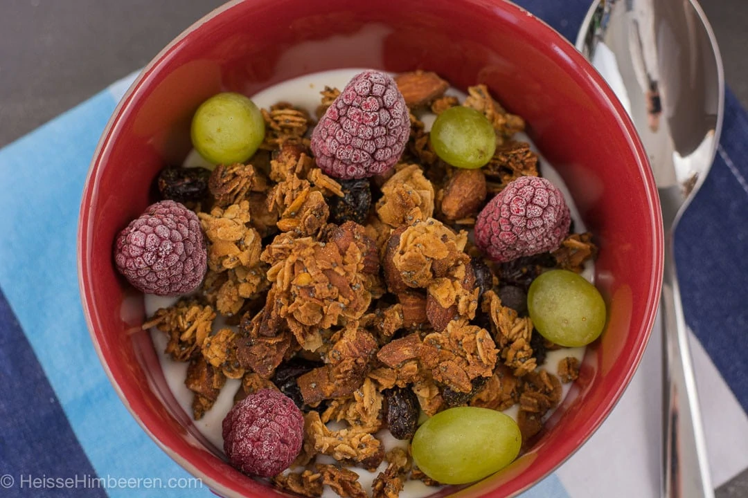 Eine Schüssel mit Winter Granola, Himbeeren Trauben und Milch