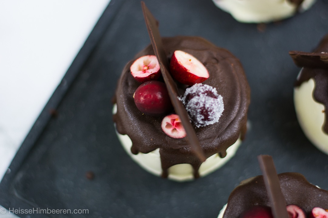Ein Mini Törtchen mit Schokolade und Cranberrys auf einer schwarzen Platte