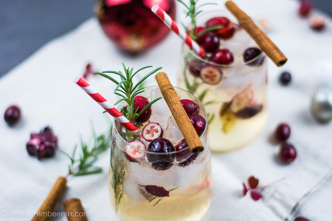 Zwei weihnachtliche Cocktails mit Rosmarin Zweigen, Cranberries und Zimtstangen
