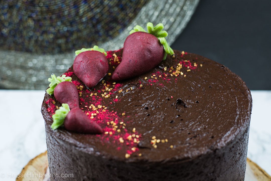 Ein saftiger Schokoladenkuchen mit Rote Bete. Auf dem Kuchen liegen Rote Beete aus Marzipan