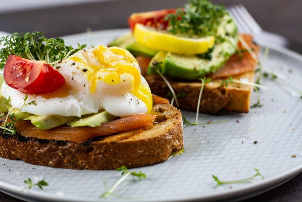 Pochiertes Ei, Avocado & Räucherlachs auf knusprigen Toast als schneller Snack.