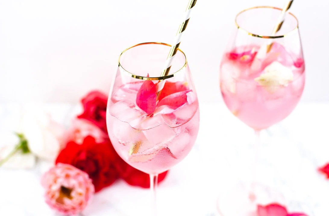 Ein Glas mit einem Pink Rose Cocktail und einem goldenen Strohhalm.