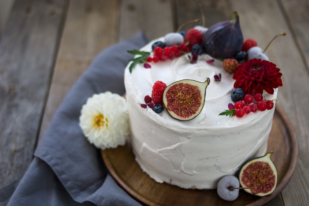 Eine weiße Geburtstagstorte mit fruchtiger Dekoration und echten Blumen
