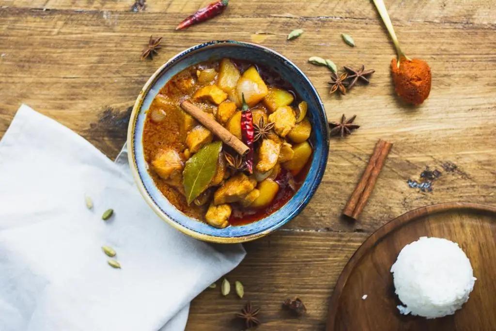 Massaman Curry vegan auf dem Tisch, neben einer Schüssel Reis.