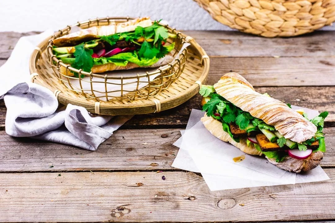 Zwei Banh Mi Baguette Sandwiches auf einem Holztisch.