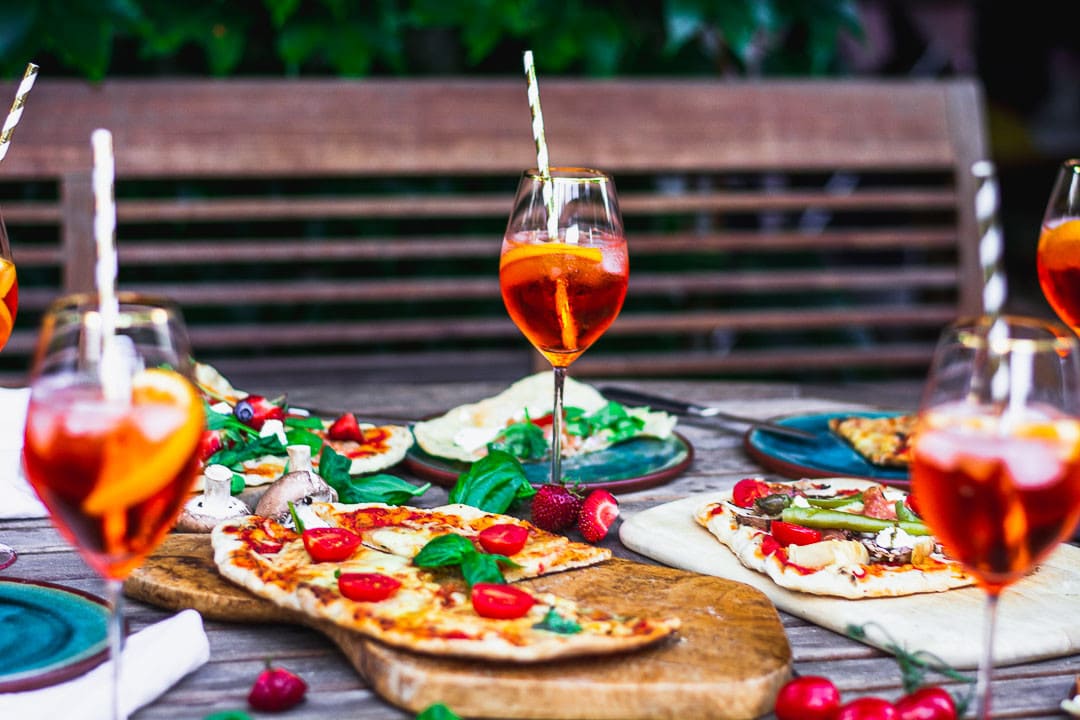 Gegrillte Pizza und Aperitifs auf einem Gartentisch