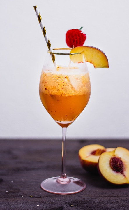 Ein Cocktail mit einem Stück Pfirsich und einem Strohhalm