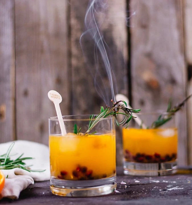 Zwei Rum Cocktails Gläser, die mit eine orangen Flüssigkeit und Cranberries gefüllt sind