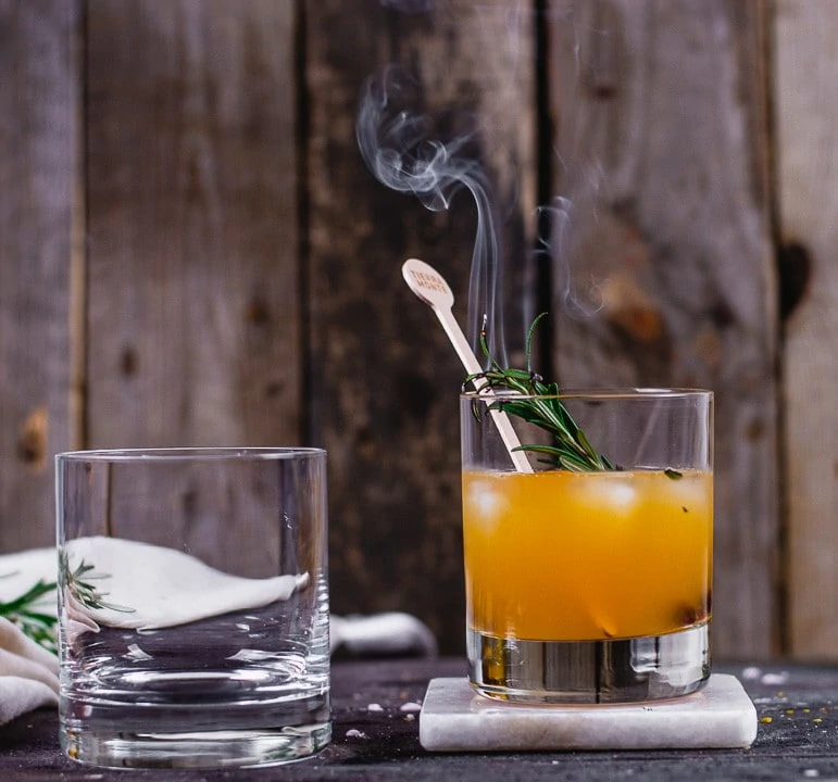 Der Rosmarinzweig raucht im Rum Cocktail