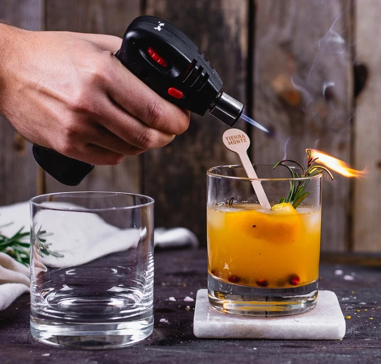 Der Rosmarinzweig des weihnachtlichen Cocktails mit Rum, wird flambiert.