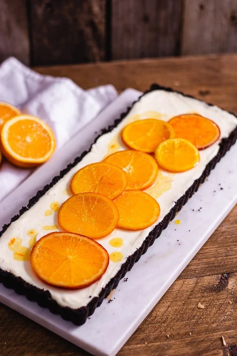 Orangentarte von der Seite auf einem Mamorbrett