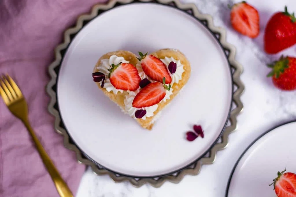 Ein Herz mit Erdbeeren und Sahne dekoriert auf einem Teller zum Muttertag