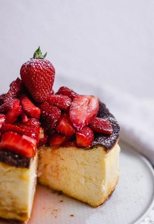 Ein angeschnittener baskischer San Sebastian Cheesecake mit Erdbeeren.