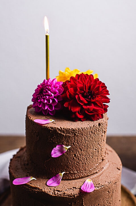 Ein schokoladiges Geburtstagstorten Rezept. Der Kuchen ist dekoriert mit Blumen und einer brennenden Kerze