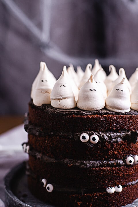 Auf der Halloween Torte sitzen kleine Geister aus Baiser. An der Seite der Torte sind Augen befestigt. Es wirkt als würde Torte einen anschauen