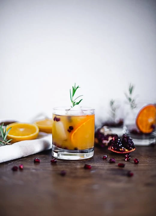 Ein Weihnachtsaperitif im Glas mit Eiswürfel, Orangen, Cranberries und Deko