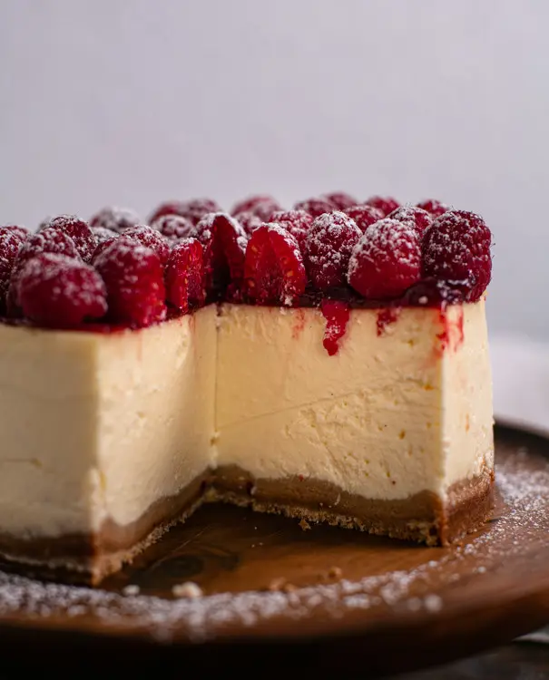 Ein angeschnittener Cheesecake mit Himbeeren.