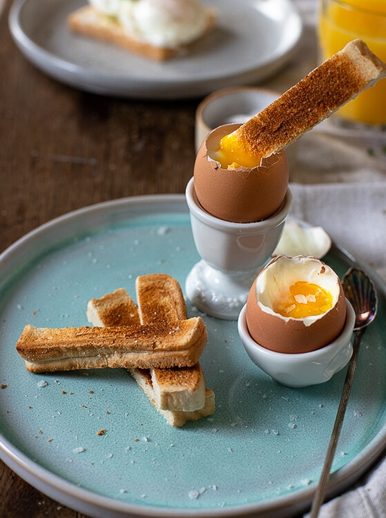 Ein stück Toastbrot wird in ein weich gekochtes Ei gedippt. Das Flüssige Eigelb wird vom Toastbrot aufgesogen. 