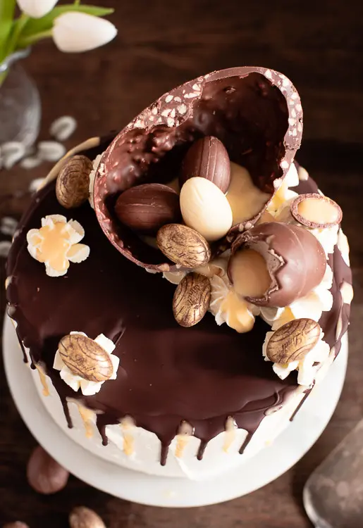 Die schokodekoration der Eierlikörtorte besteht aus einem halben, großen Schoko Osterei mit Nuss, damit mit mehreren kleinen Schoko Ostereiern gefüllt ist.