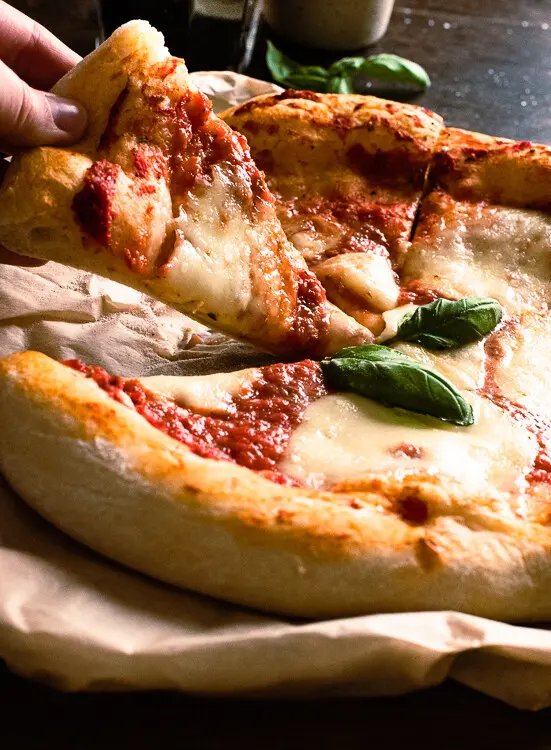 Diese Pizza Margarita ist eine 5 Minuten Pizza. Ein Stück wird aus der Pizza genommen. Der geschmolzene Käse ist gut zu erkennen. 