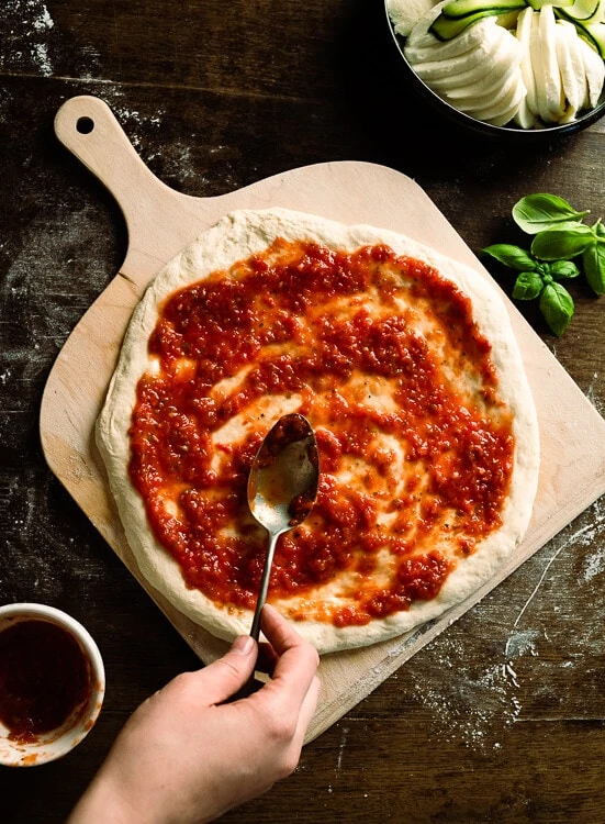Die Pizza wird nun mit einem Löffel mit Tomatensauce bestrichen. 