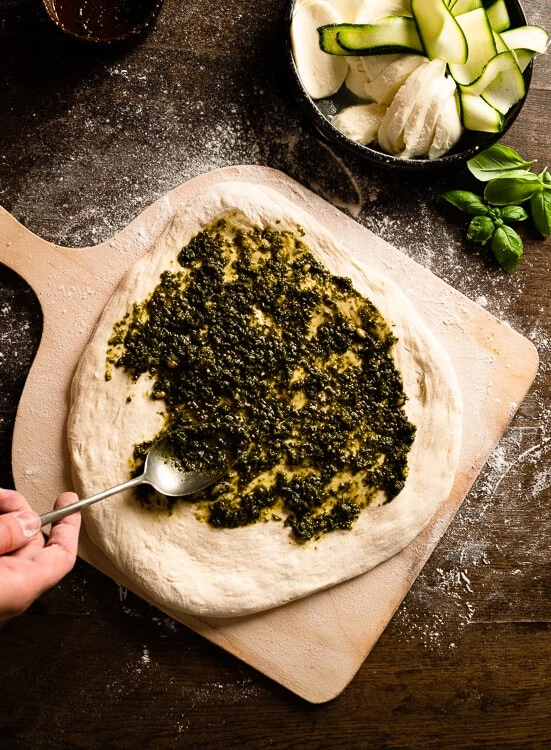 Pesto Genovese wird auf einen vorbereiteten Pizzateig gestrichen