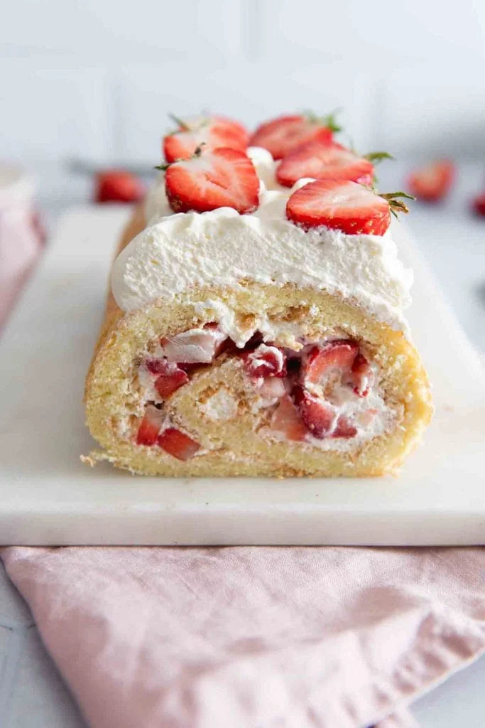 Eine Erdbeer Biskuitrolle mit leckeren Erdbeeren auf dem Tisch.