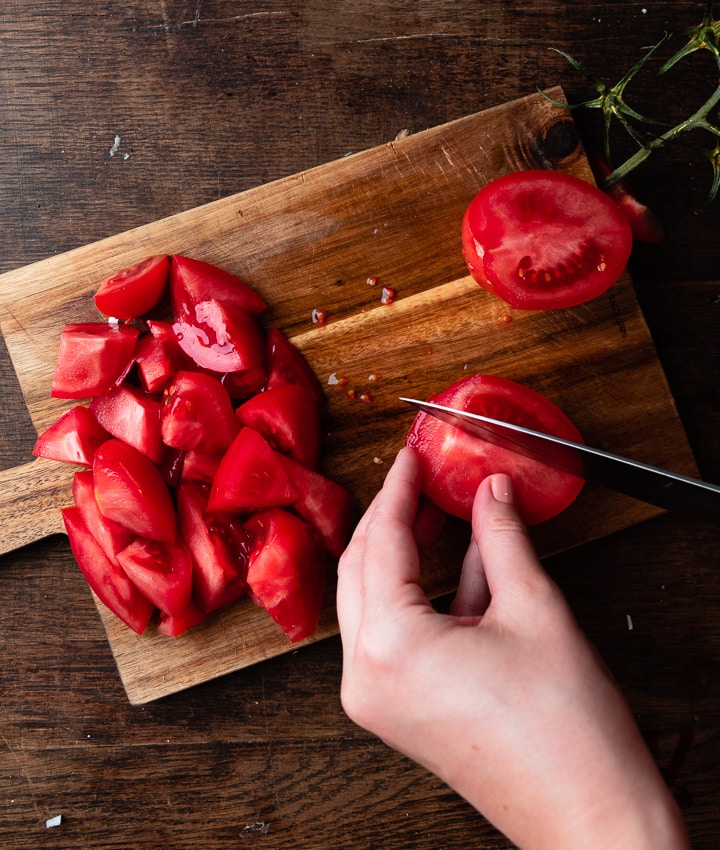 Eine frische Tomate wird halbiert mit einem Messer.