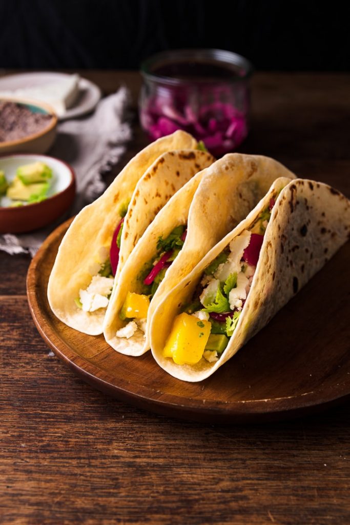 Drei leckere vegetarische Tacos auf einem Tisch.
