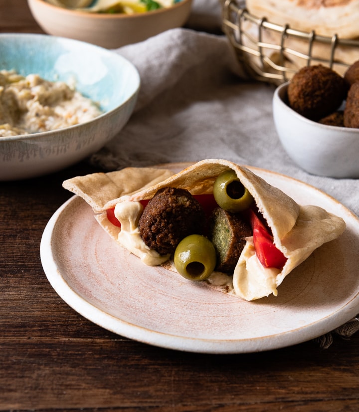 Ein gefülltes Pita Brot mit Falafel, Oliven und Hummus.