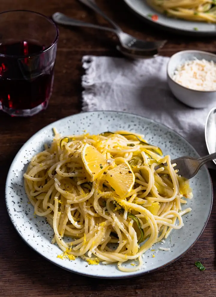 Eine Gabel nimmt Zitronen Spaghetti mit Zucchini auf.