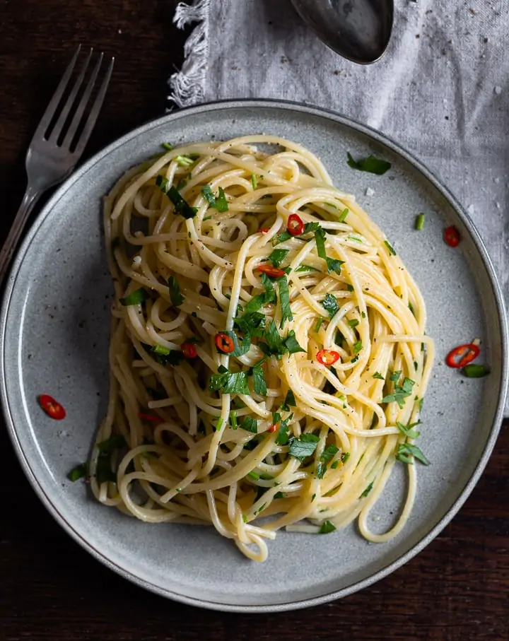 Ein Teller Spaghetti Aglio e Olio mit einer Gabel daneben.