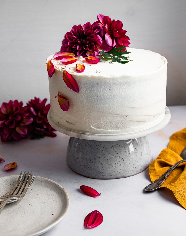 Eine weiße Geburtstagstorte auf einem Teller mit frischen Blumen.