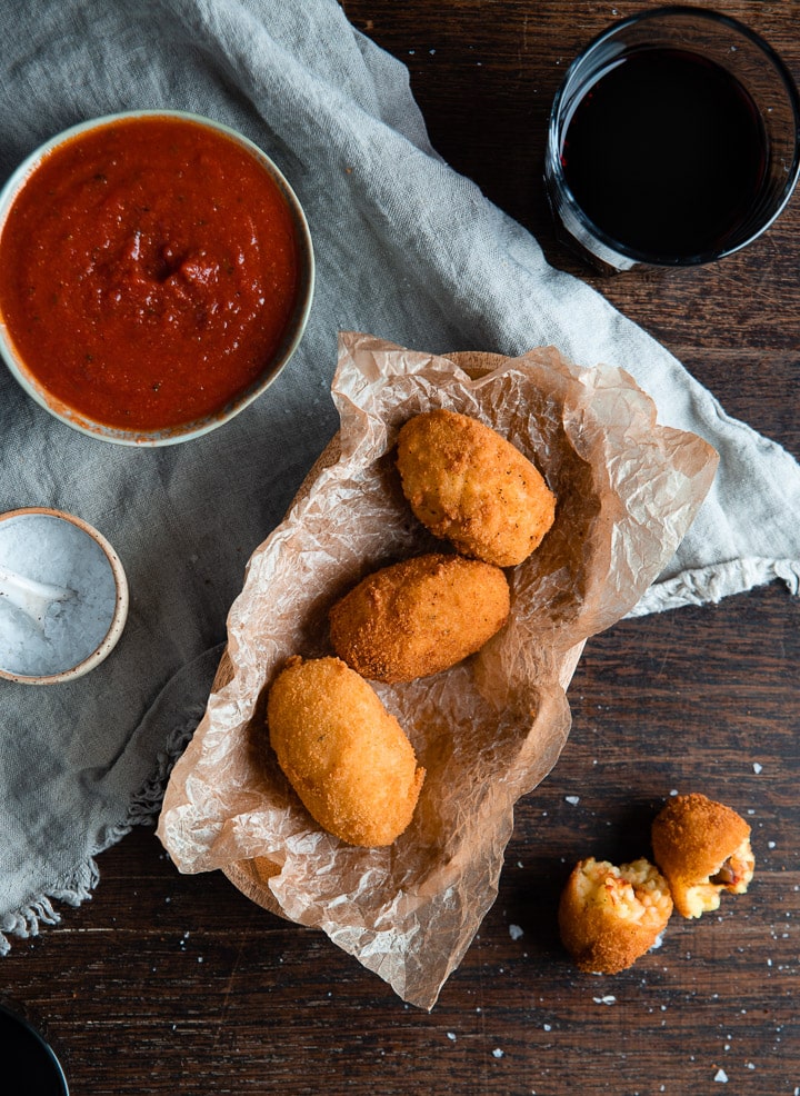 Drei vegetarische Arancinis liegen neben dem Tomatensaucendip.