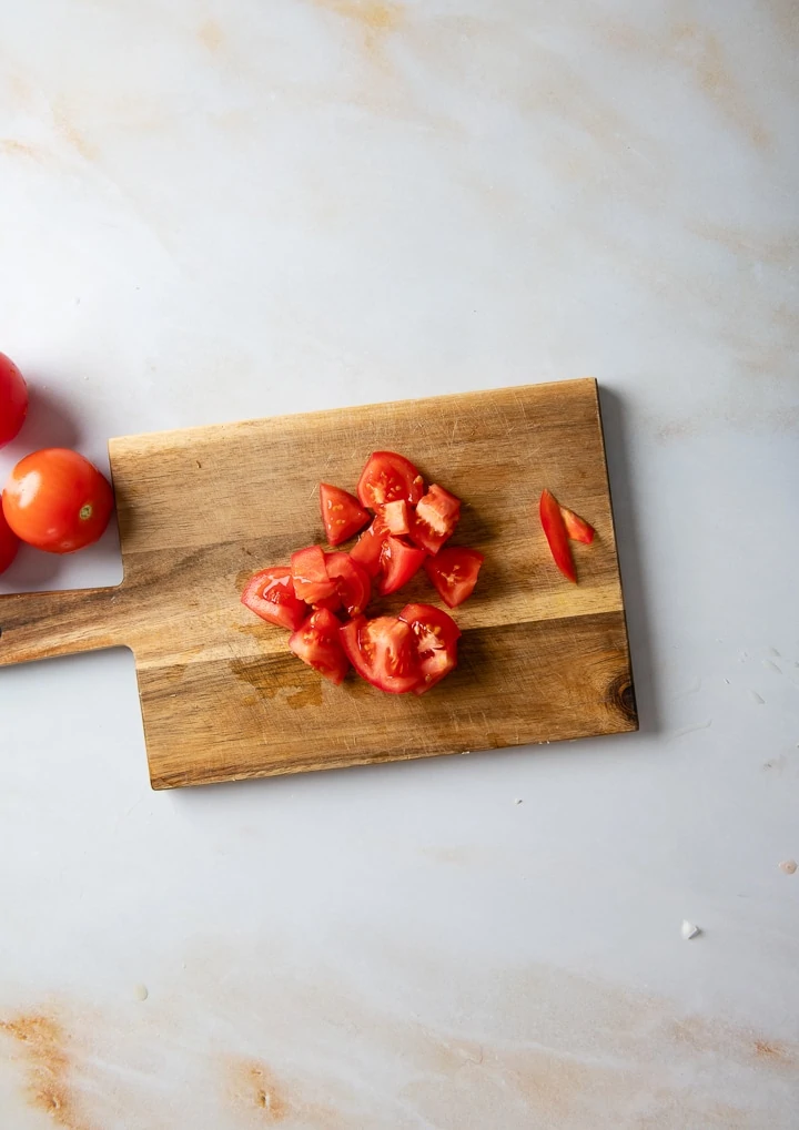 Tomaten werden auf einem Brett gewürfelt.