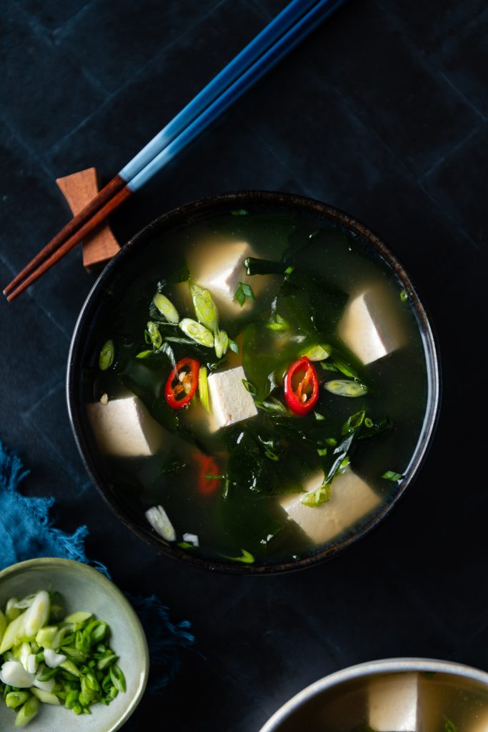 Eine vegane Miso Suppe mit Tofu und Stäbchen.