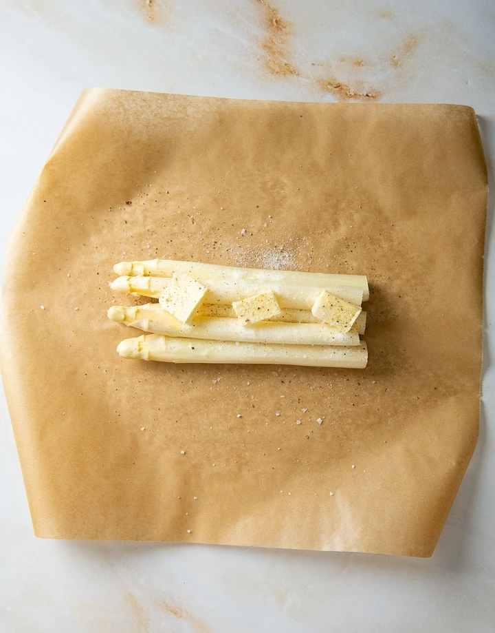 Weißer Spargel wird mit Butter und Salz eingewickelt und im Backofen gebraten.