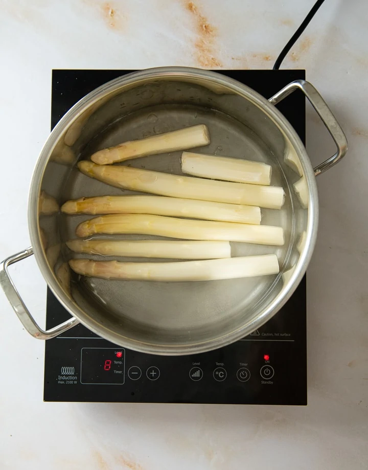 Weißer Spargel wird in einem Kochtopf in Wasser gekocht.