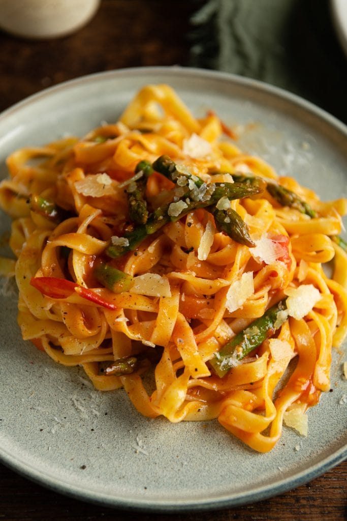 Eine vegetarische Pasta mit Spargel, Tomaten und Parmesan oben drauf.