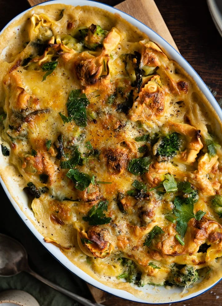 Was koche ich heute? Wie wäre es mit einem vegetarischen Tortellini-Auflauf mit Brokkoli in einer cremigen Käse-Sahne-Soße, goldbraun überbacken und mit Petersilie bestreut, in einer ovalen Auflaufform.