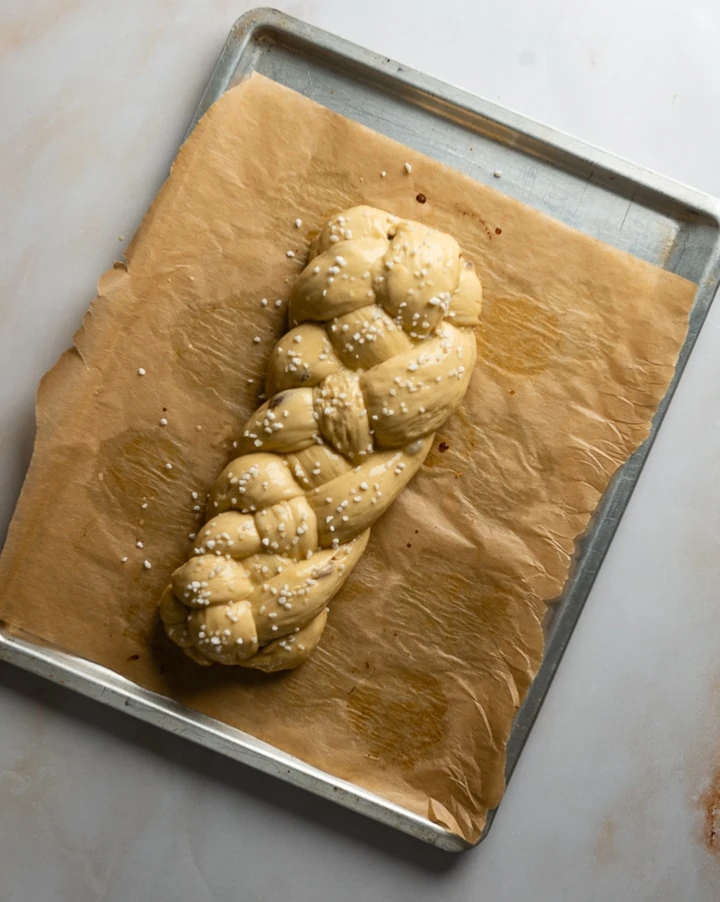 Der süße Hefezopf liegt auf einem Blech und kommt gleich in den Ofen.