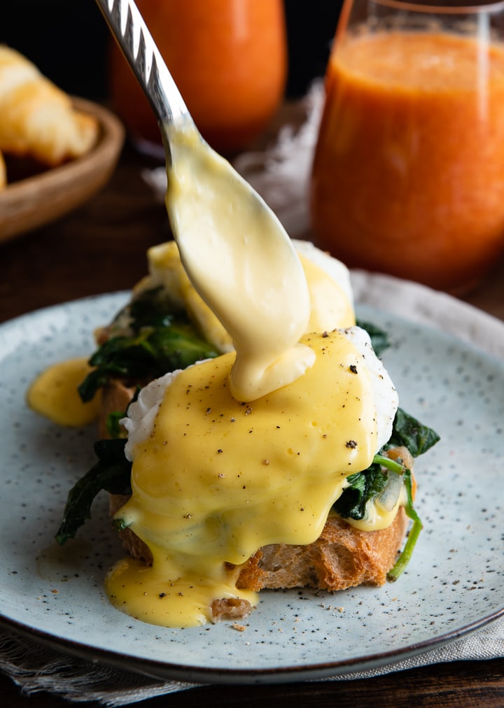 Sauce Hollandaise wird auf das pochierte Ei & Toast gegeben.