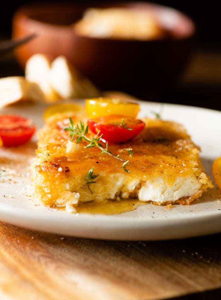 Der fertige panierter schafskäse mit Honig und Tomaten.