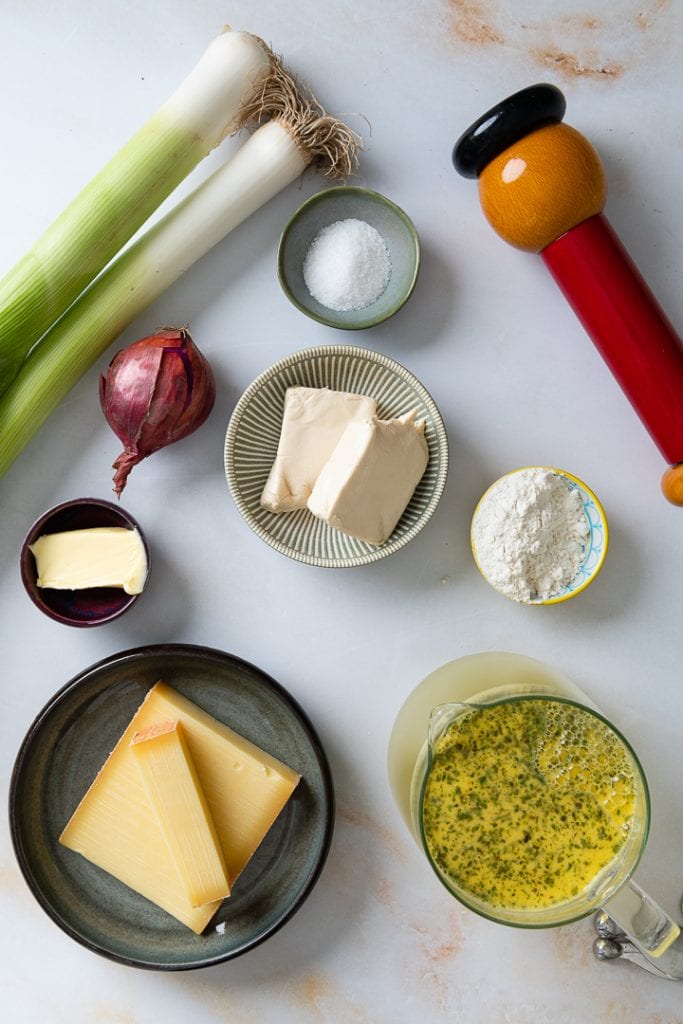 Die Zutaten für die vegetarische Käsesuppe liegen auf einer Marmorplatte.