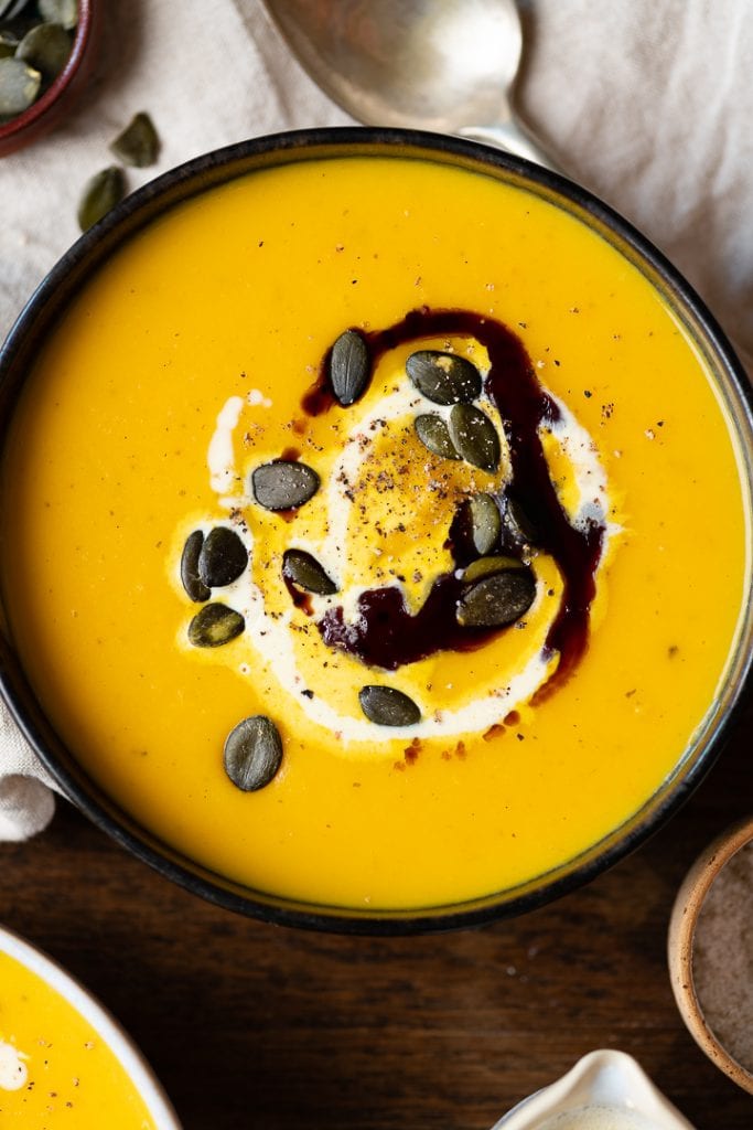 Ein Teller Kürbis-Kartoffel-Suppe auf dem Tisch.