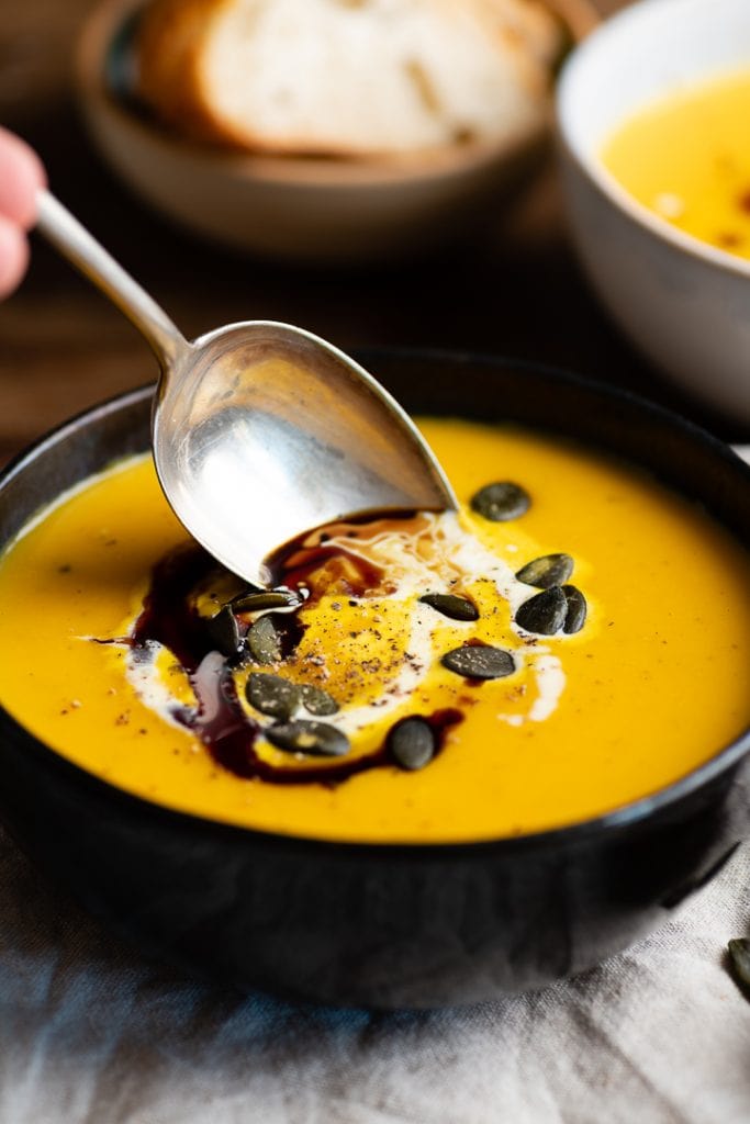 Ein Löffel geht in die kürbis kartoffel suppe.