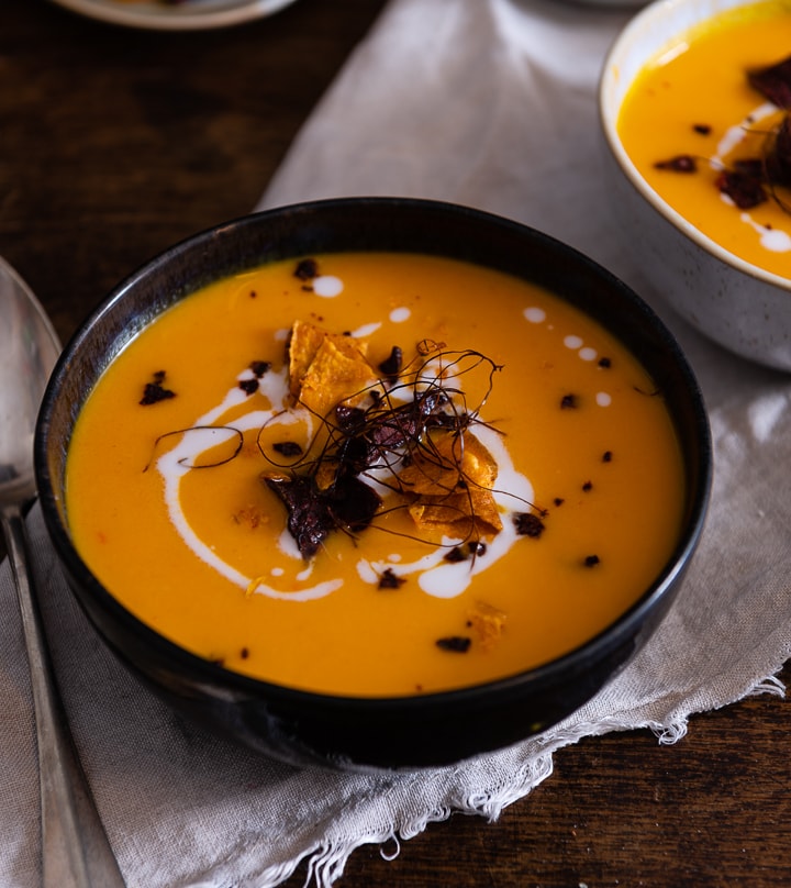 Ein Löffel neben der karotten ingwer kokos suppe.